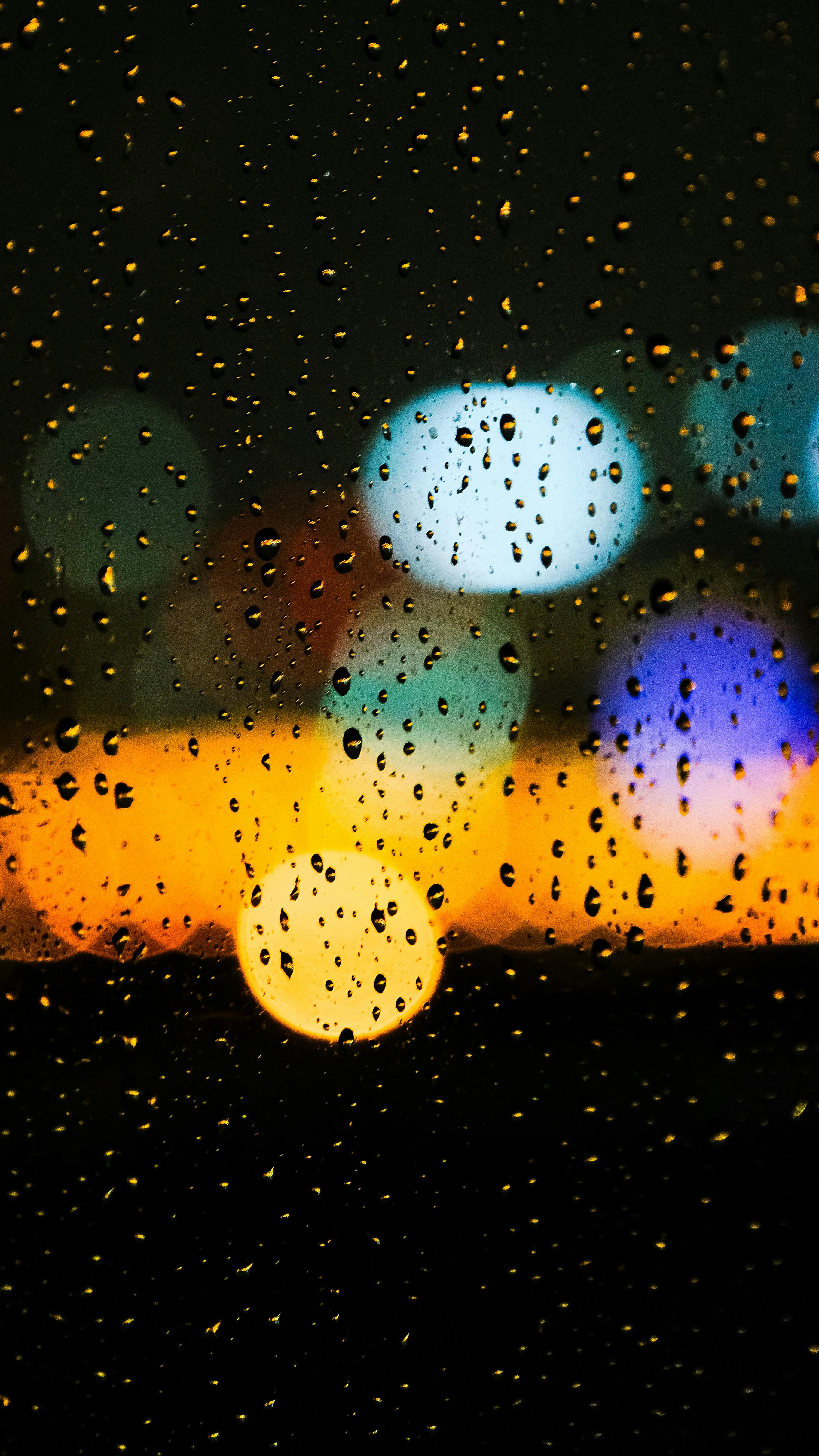 城市夜幕下的梦幻之夜，玻璃上的雨滴映照城市光彩