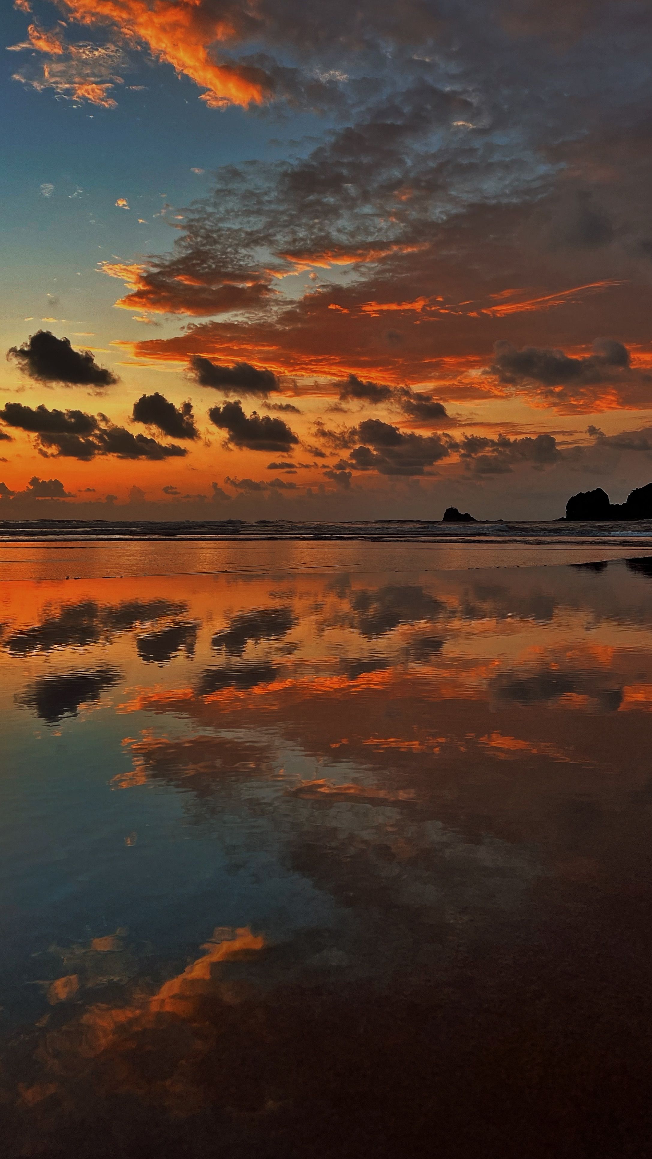 A Stunning Reflection Of The Sunset On Canaguinim Beach, India With Vibrant Clouds And Serene Waters.