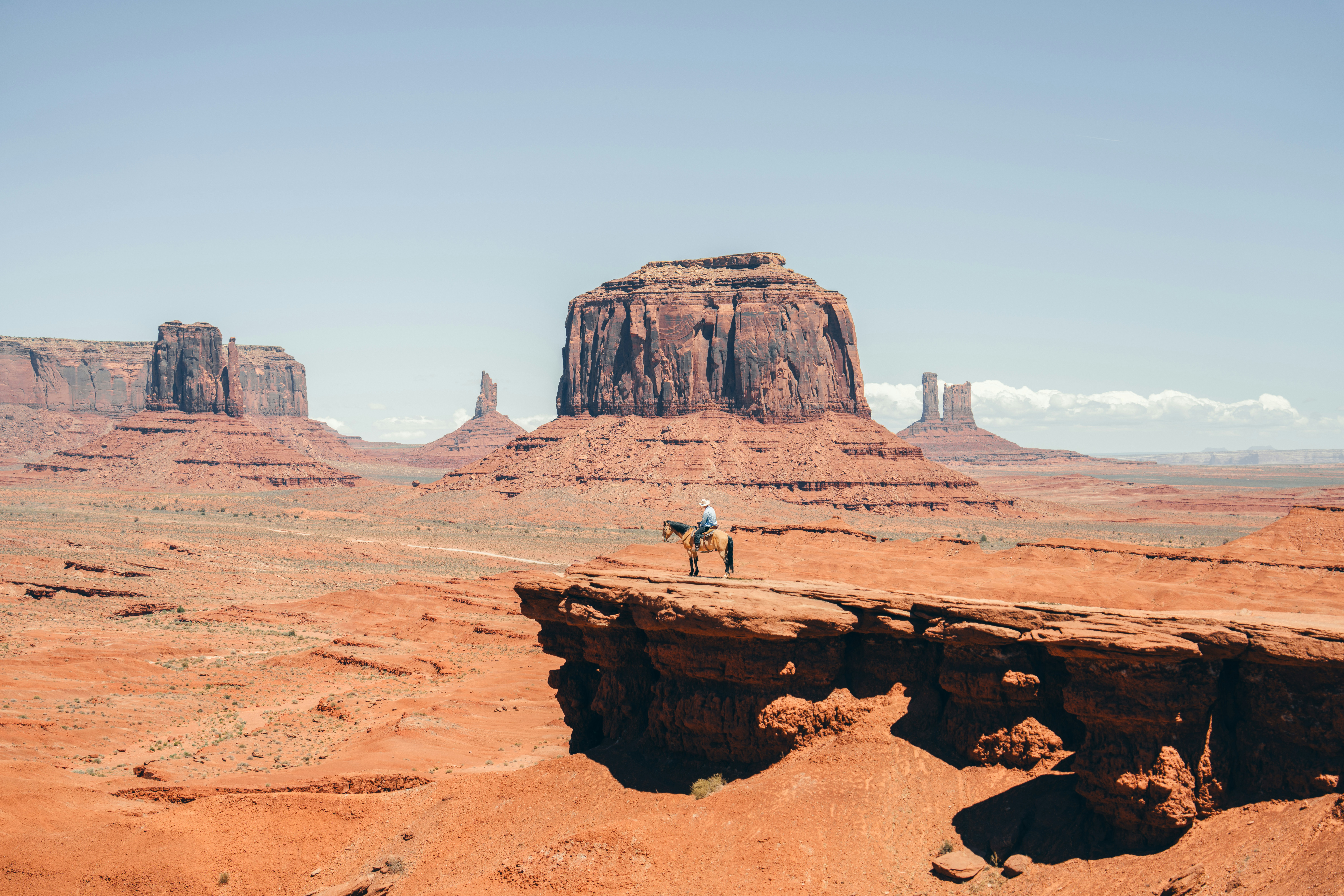 Lone Figure Stands On Cliff Edge In Monument Valley.
