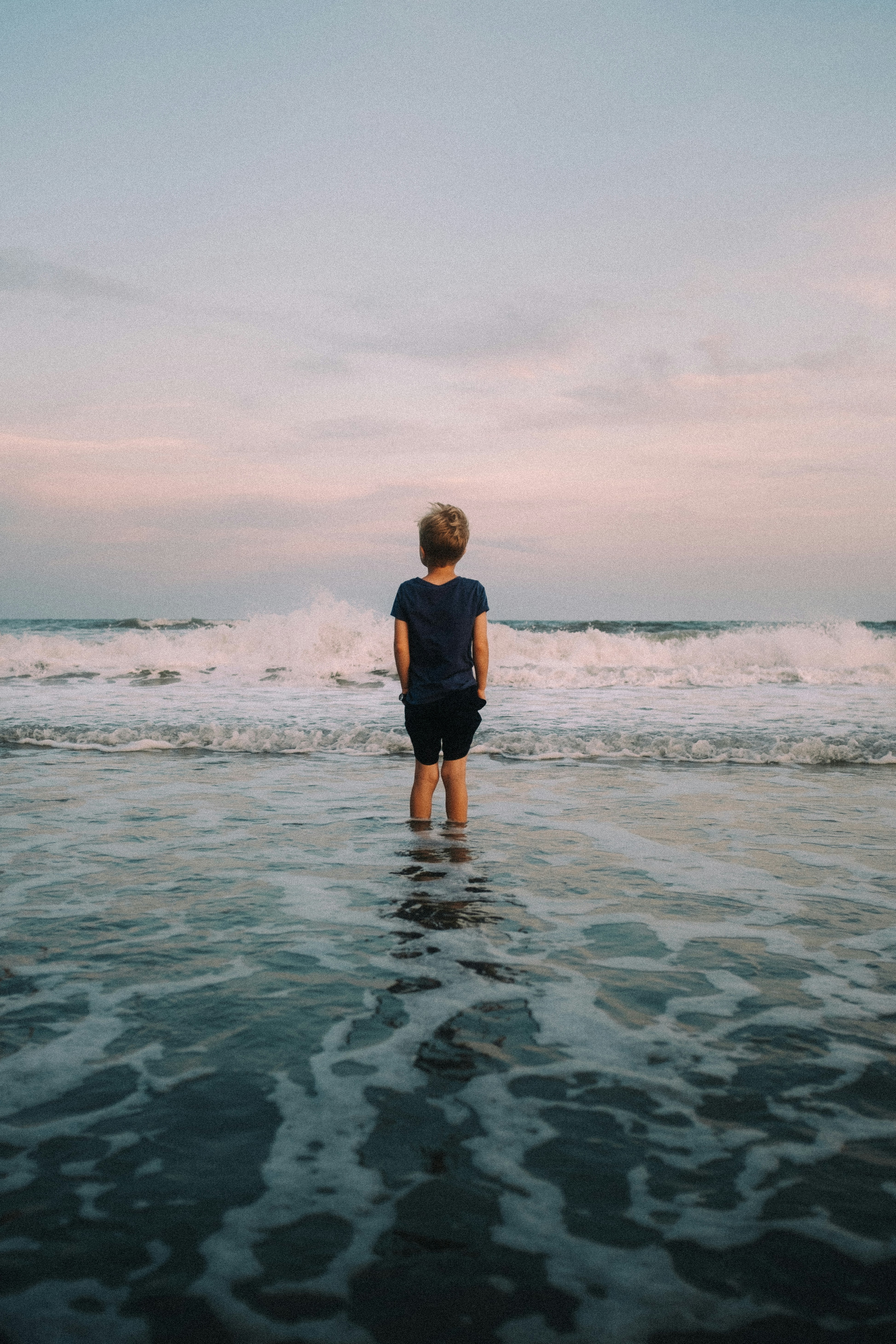年少的少年站在日落海浪中