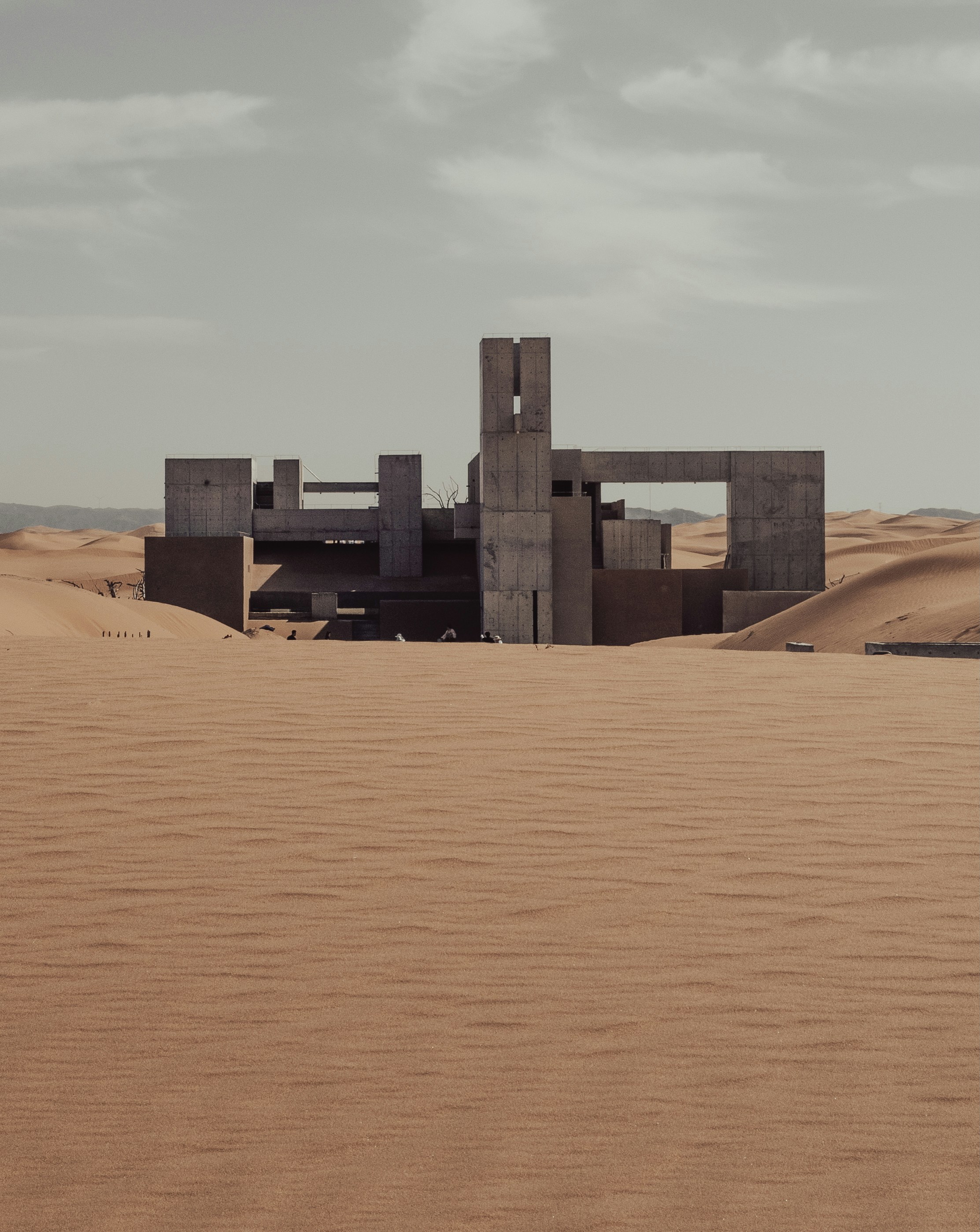 A Brutalist Concrete Building Stands Isolated In A Vast Desert.