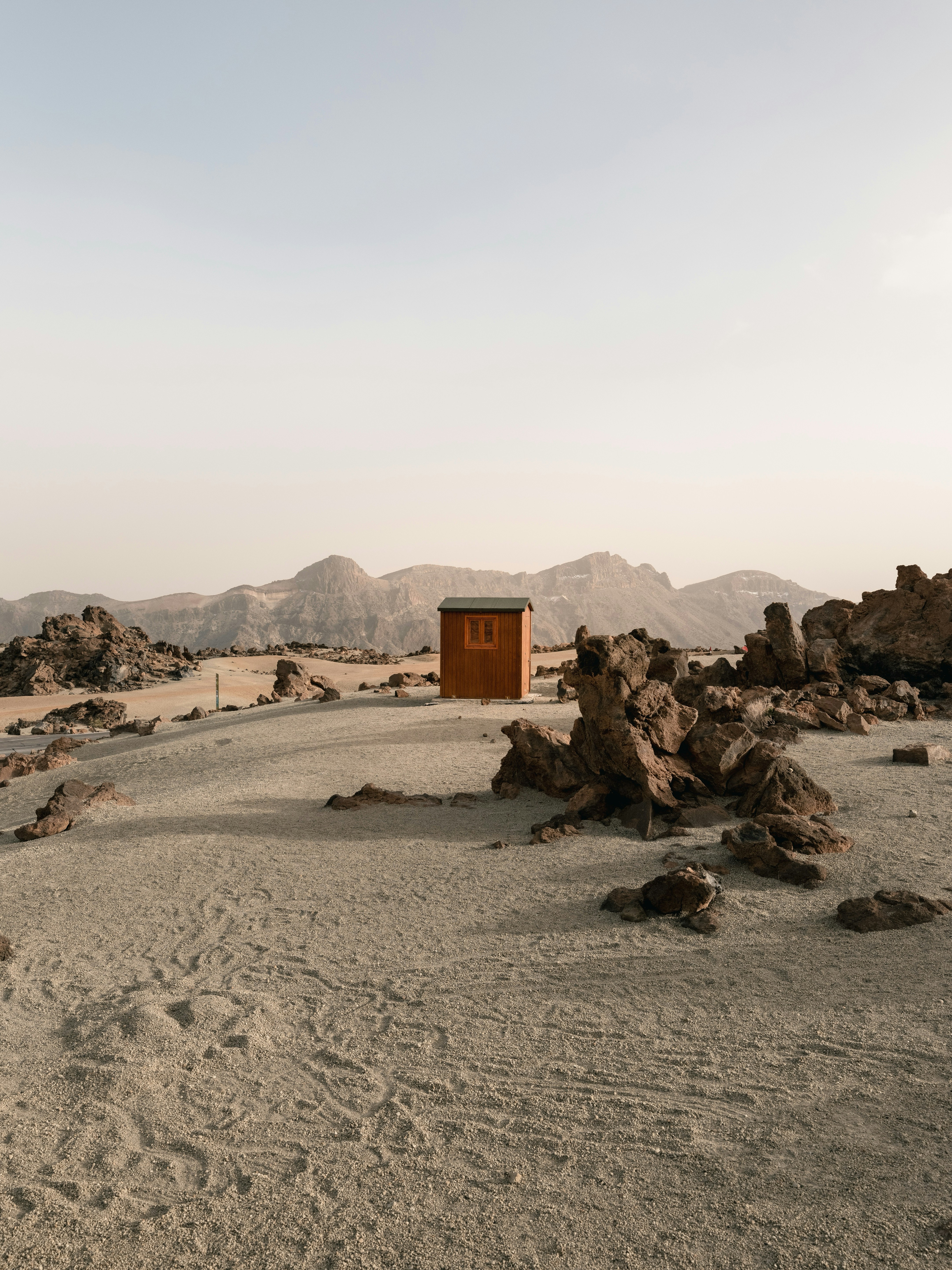 A Small Wooden Cabin In A Vast, Rocky Desert Landscape.