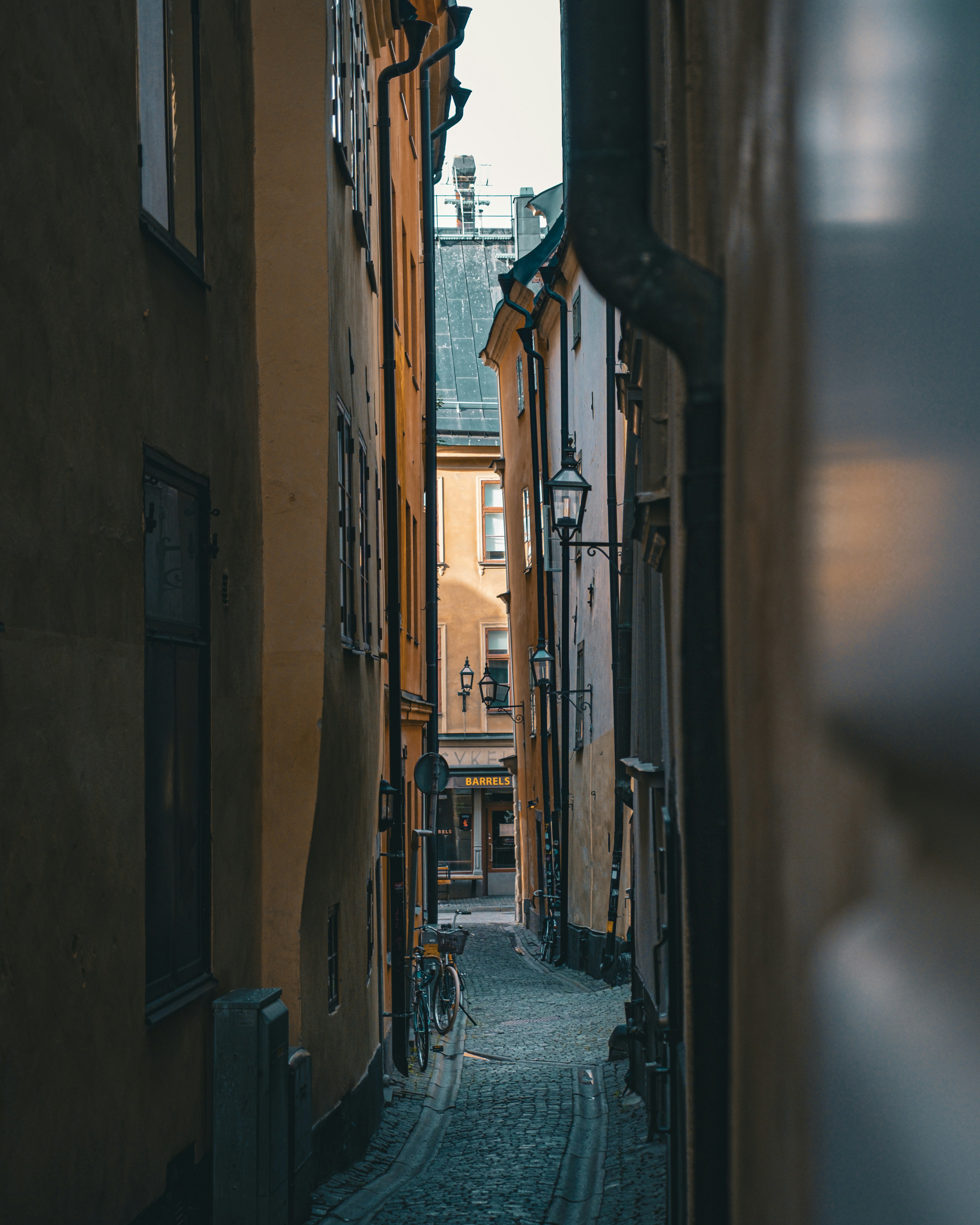 Cobblestone Street In Gamla Stan, Stockholm's Medieval Old Town, Lined With Colorful Historic Facades In Warm Ochre And Terracotta Tones With A Bicycle In The Distance