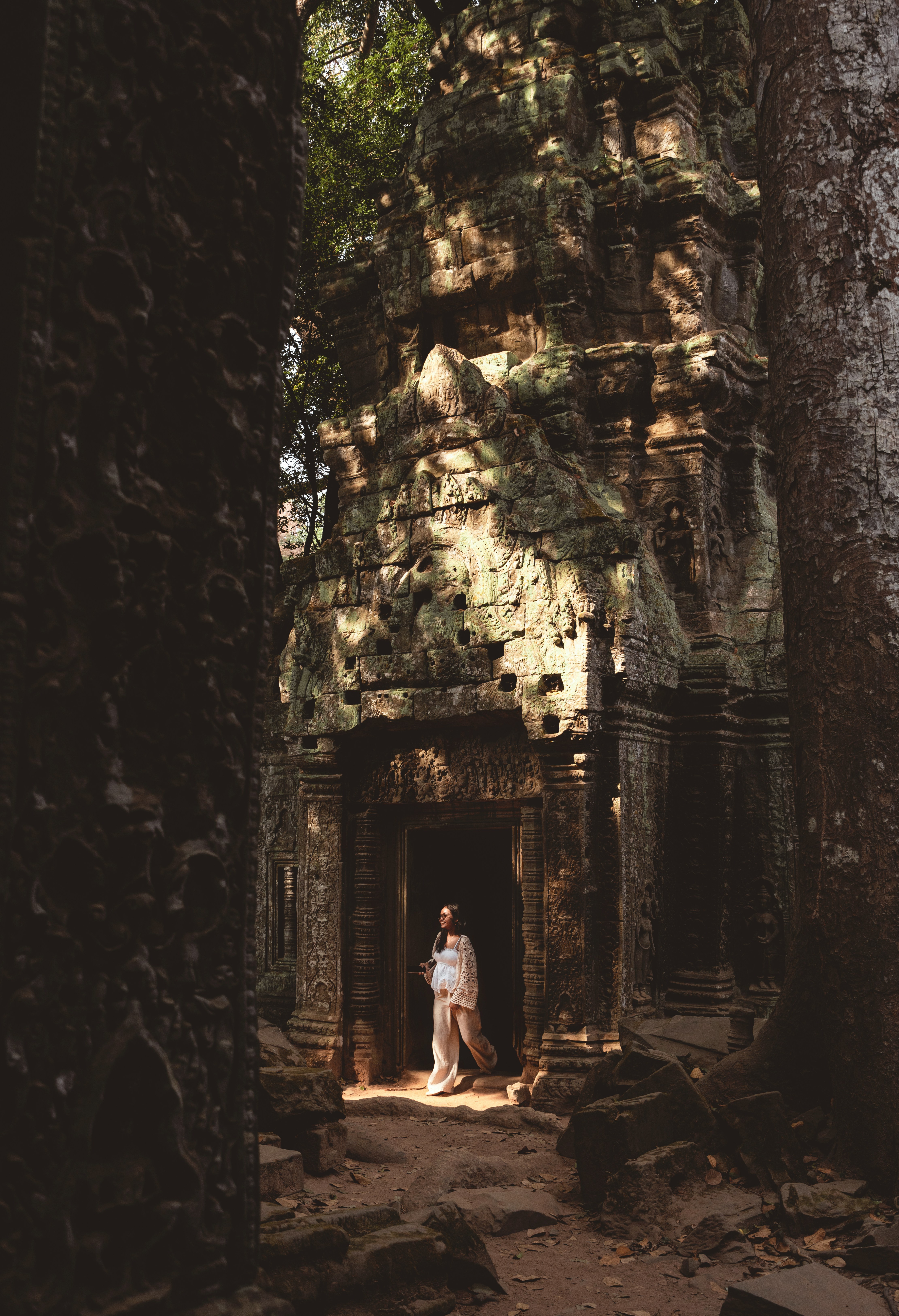 Woman Walking From Ancient Temple Entrance Framed By Trees.