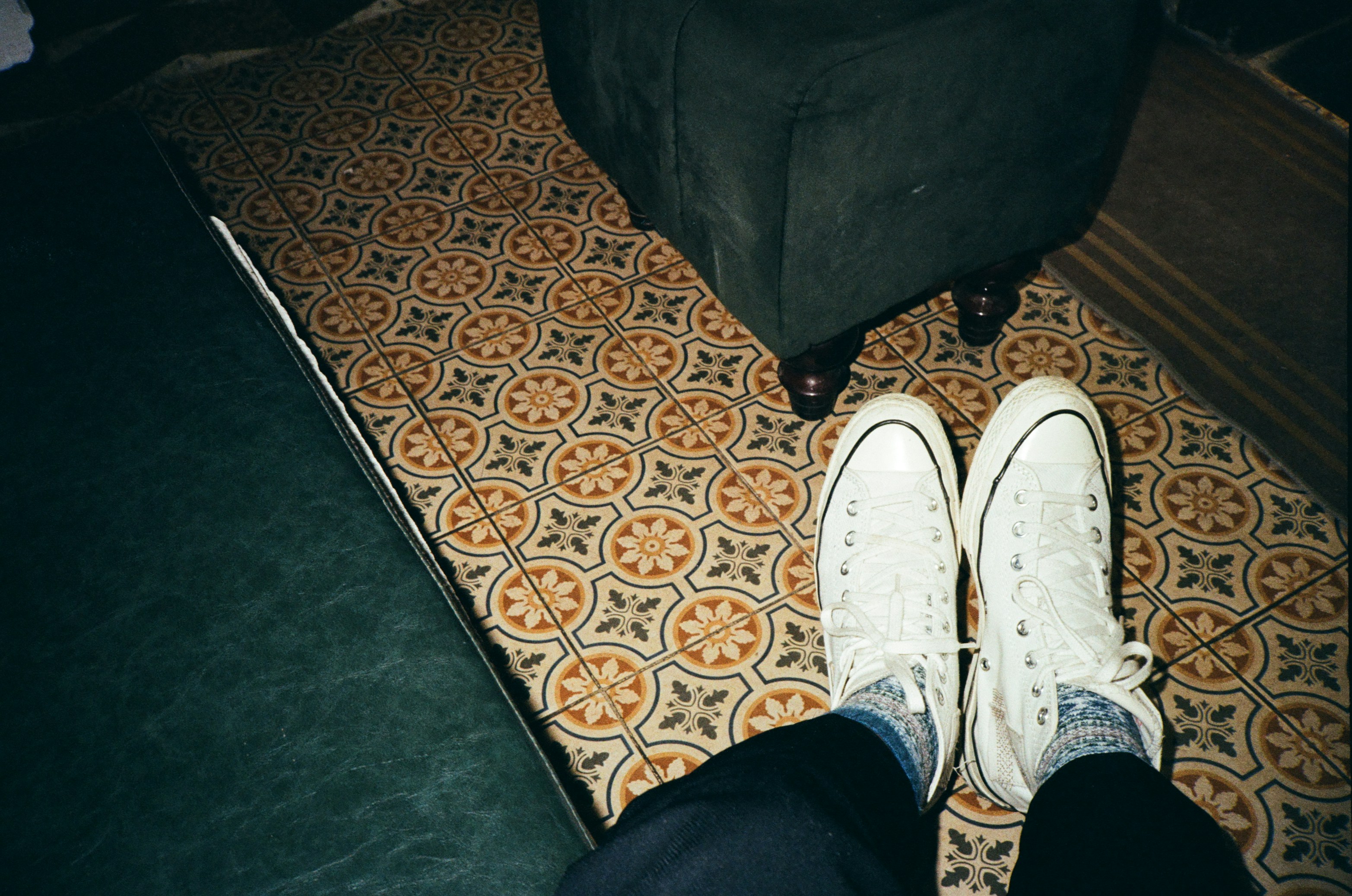 White Sneakers On Patterned Rug With Dark Furniture.