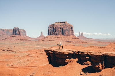 Lone Figure Stands On Cliff Edge In Monument Valley. wallpaper preview