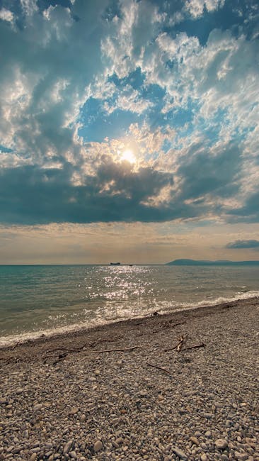 A Tranquil Pebble Beach Scene With Gentle Waves Under A Vibrant Sunrise Sky. wallpaper preview