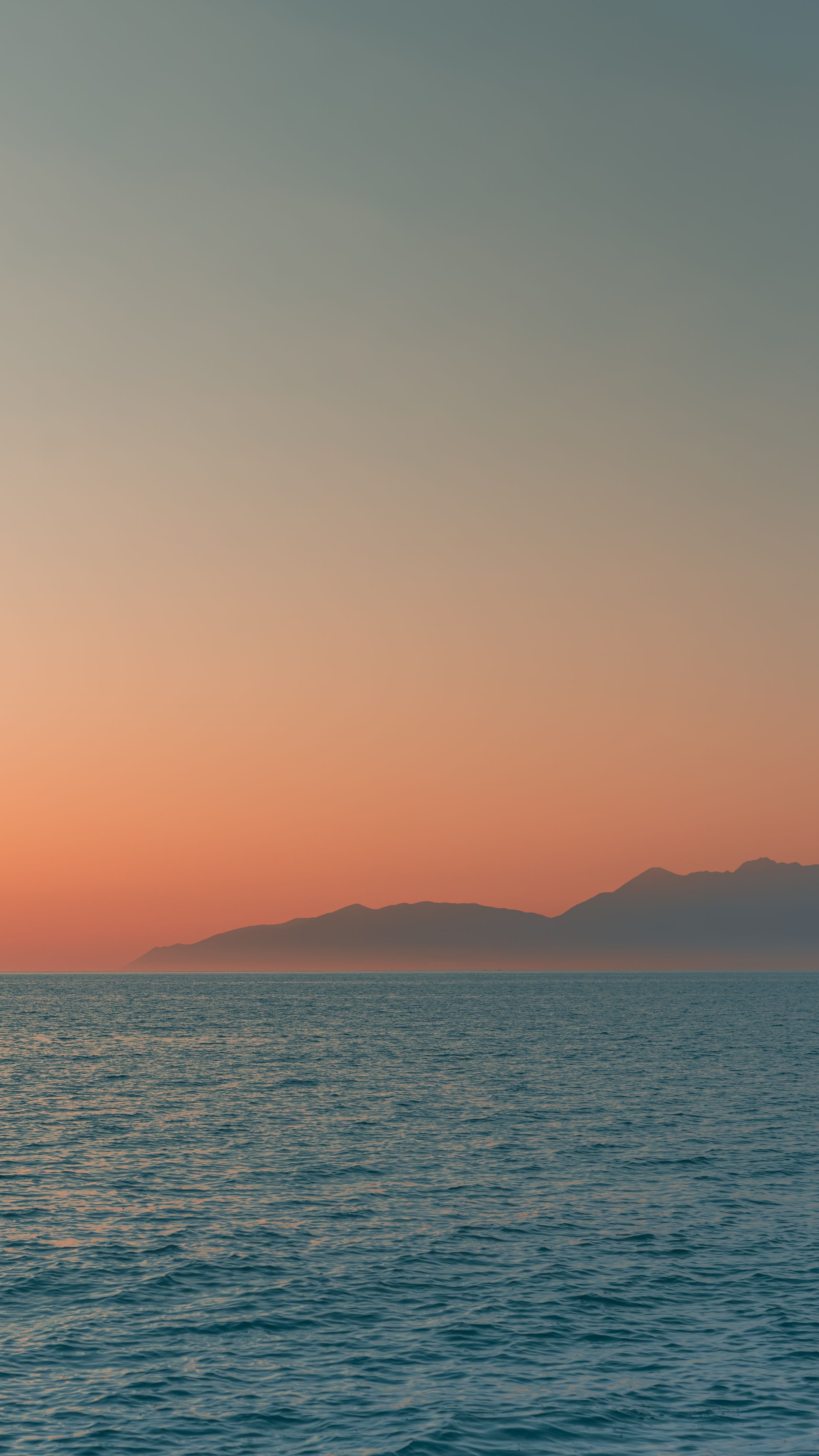 在希腊科孚岛的宁静海洋中，远山下的夕阳余晖手机壁纸高清图片