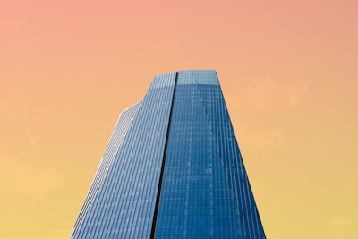 Tall Glass Skyscraper Against Orange And Yellow Gradient Sky wallpaper preview