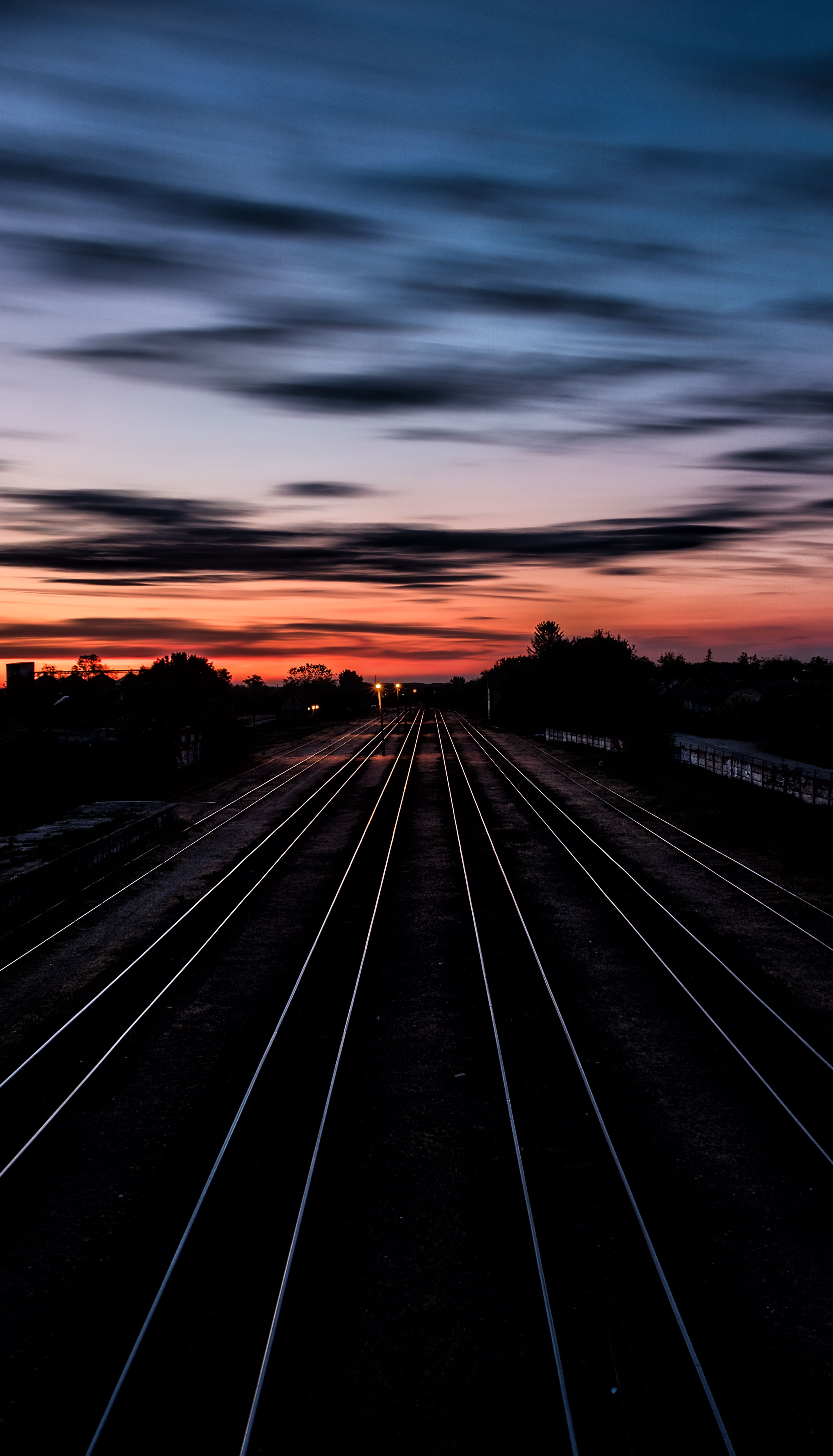 Long Railway Tracks Stretching Into The Horizon Under A Dramatic Twilight Sky. HD mobile wallpaper