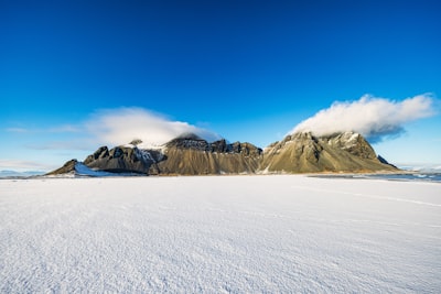 遙遠的雪原與青山相遇，白雲低垂在碧藍的天空下桌布預覽