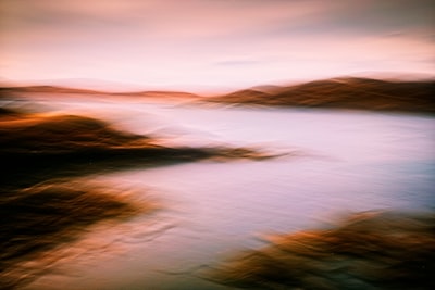 A Quiet Highland Loch Under An Overcast Sky, Where Soft Light Settles Across Water And Bracken-covered Shores. Captured Using Intentional Camera Movement, Transforming A Fleeting Moment Of Stillness Into An Atmospheric Impression Of The Scottish Landscape.
