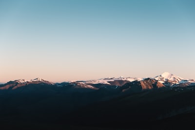Snow-capped Mountains Under A Clear Sky At Sunrise.