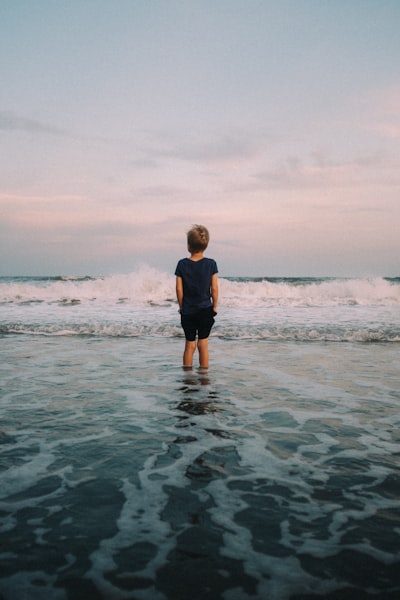 年少的少年站在日落海浪中壁纸预览