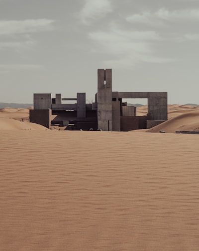 A Brutalist Concrete Building Stands Isolated In A Vast Desert. wallpaper preview
