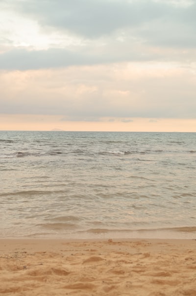 Sandy Beach, Calm Ocean, And Soft Cloudy Sky.