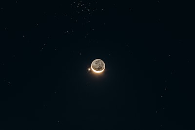半圆月亮与光芒万丈的星星在漆黑的星空中对峙
