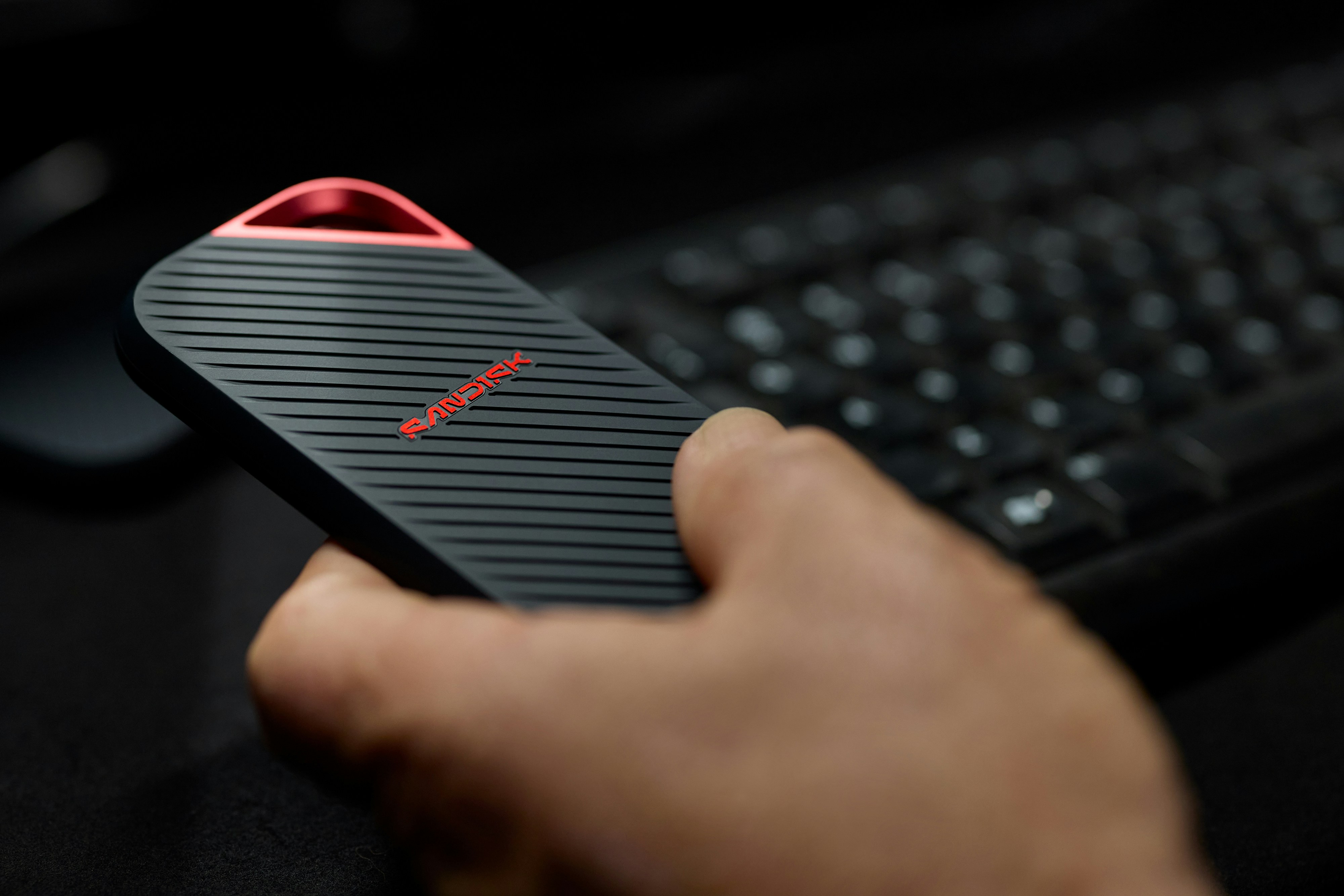 Hand Holds Black Device With Red Light Near Keyboard. HD mobile wallpaper