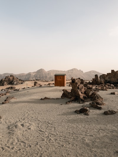A Small Wooden Cabin In A Vast, Rocky Desert Landscape.
