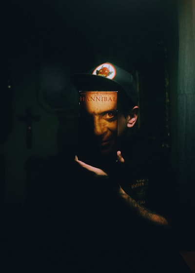 Person Holding A "hannibal" Book In A Dark Room.