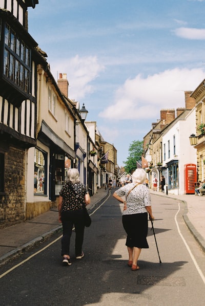 Two Elderly Women Walk Down A Charming Old Town Street.