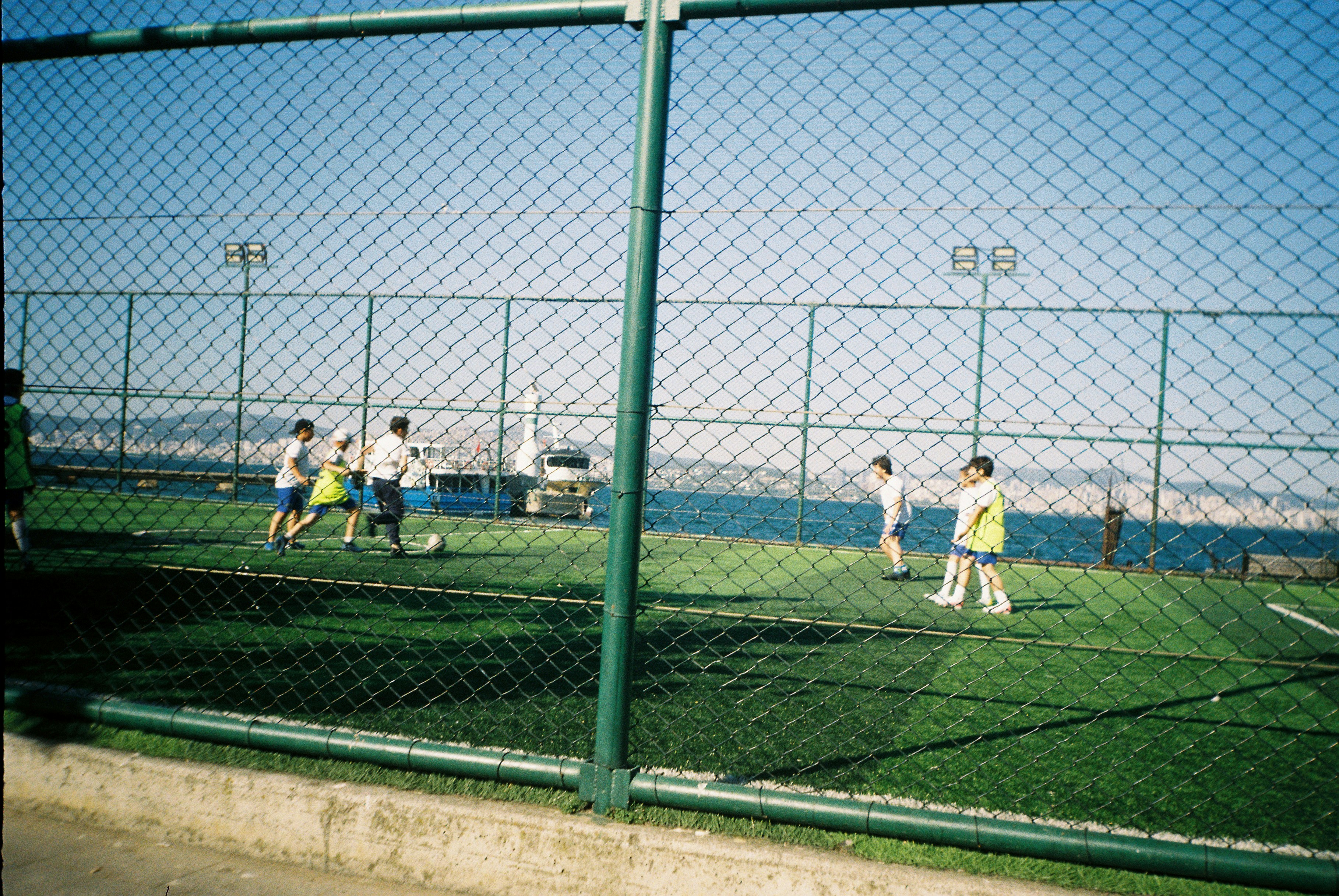 Children Play Soccer On A Turf Field Near The Ocean. HD mobile wallpaper