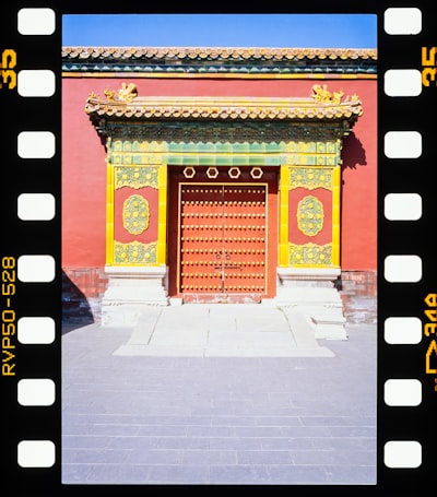 Vibrant Red Traditional Chinese Door With Ornate Yellow Roof.