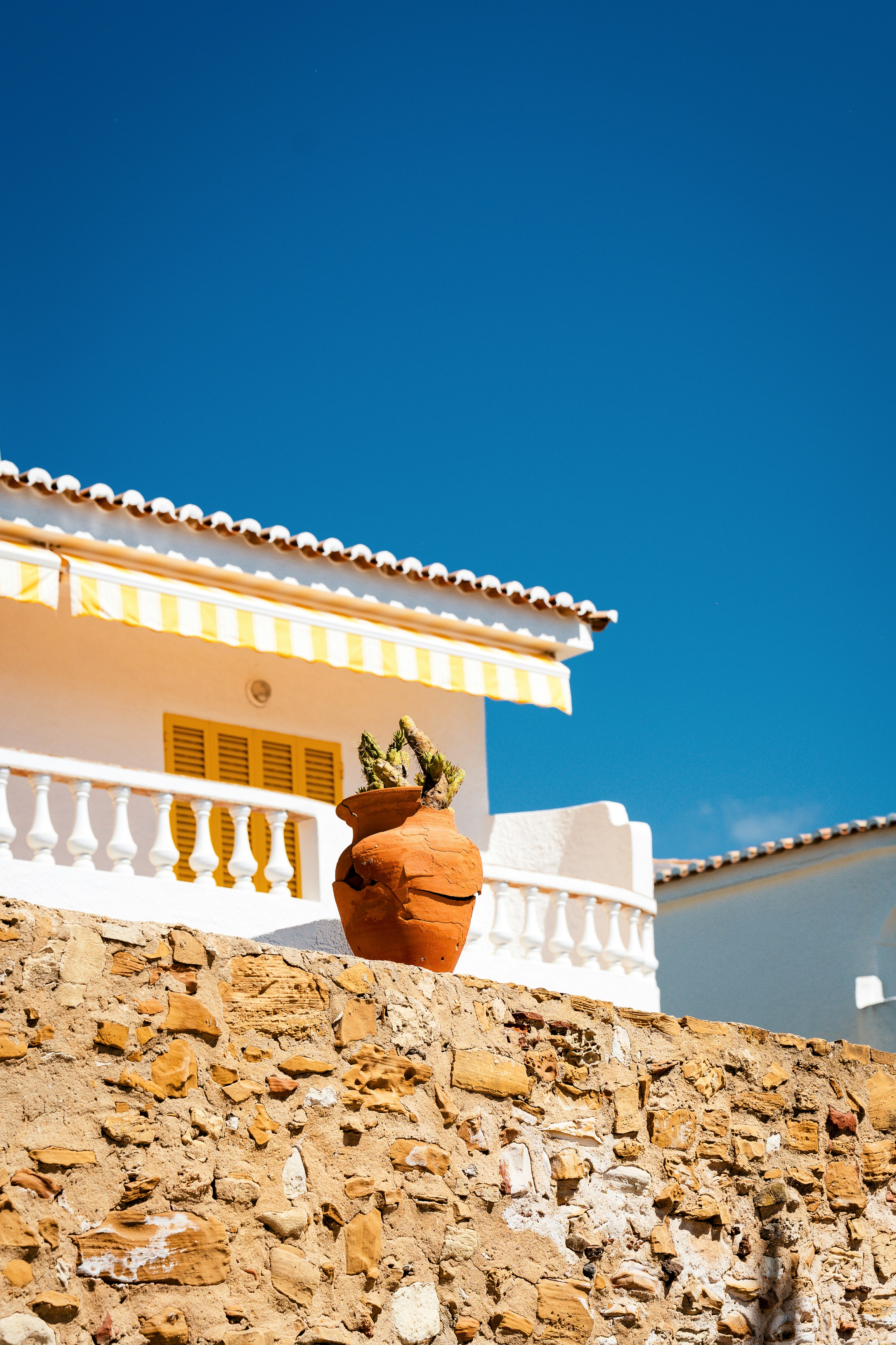 Mediterranean Building With Yellow Awning And Potted Plant. HD mobile wallpaper
