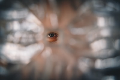 A Blue Eyed Woman Looking Through A Hole In The Glass
