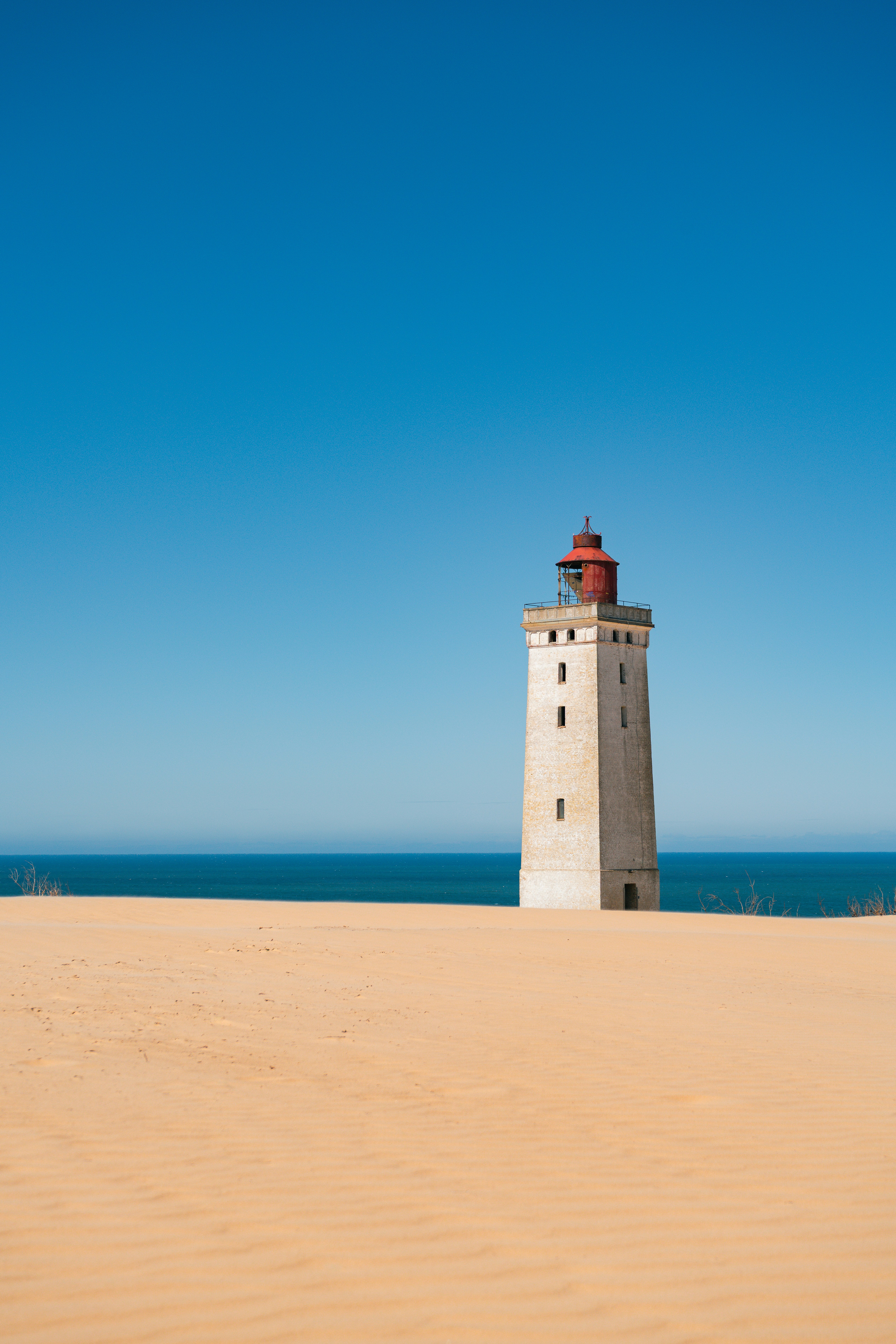 Historic Lighthouse On Vast Sand Dunes Under Clear Blue Sky. HD mobile wallpaper