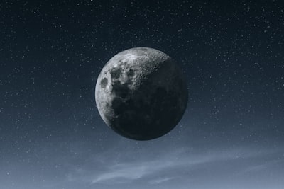 A Striking Close-up Of The Moon Dominates The Night Sky, Revealing Intricate Craters, Rugged Terrain, And Contrasting Light And Shadow Across Its Surface. Countless Stars Sparkle In The Dark Blue Sky, While A Thin Layer Of Soft Clouds Drifts Along The Lower Edge Of The Frame, Adding Depth And Atmosphere. The Composition Creates A Peaceful Yet Dramatic View Of The Moon Suspended Above The Earth. wallpaper preview