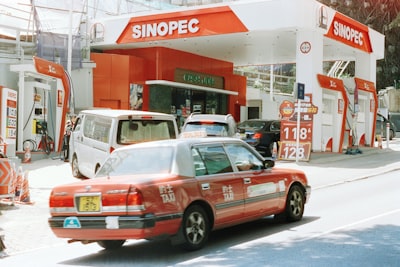 Red Taxi Driving Past A Sinopec Gas Station. wallpaper preview