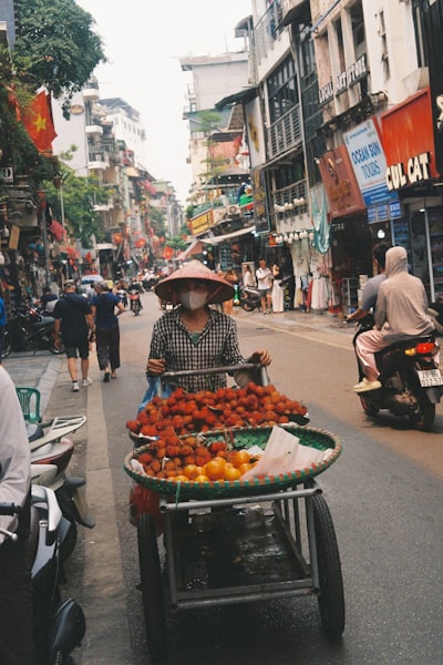 都市裡的一位婦人戴著尖頂帽子，推著水果攤桌布預覽