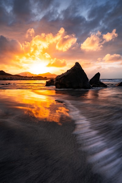 夕阳落山在岩石海滩上，波涛汹涌的壮丽景象壁纸预览