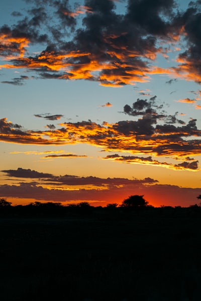 A Vibrant Sunset With Orange Clouds Over A Dark Horizon.