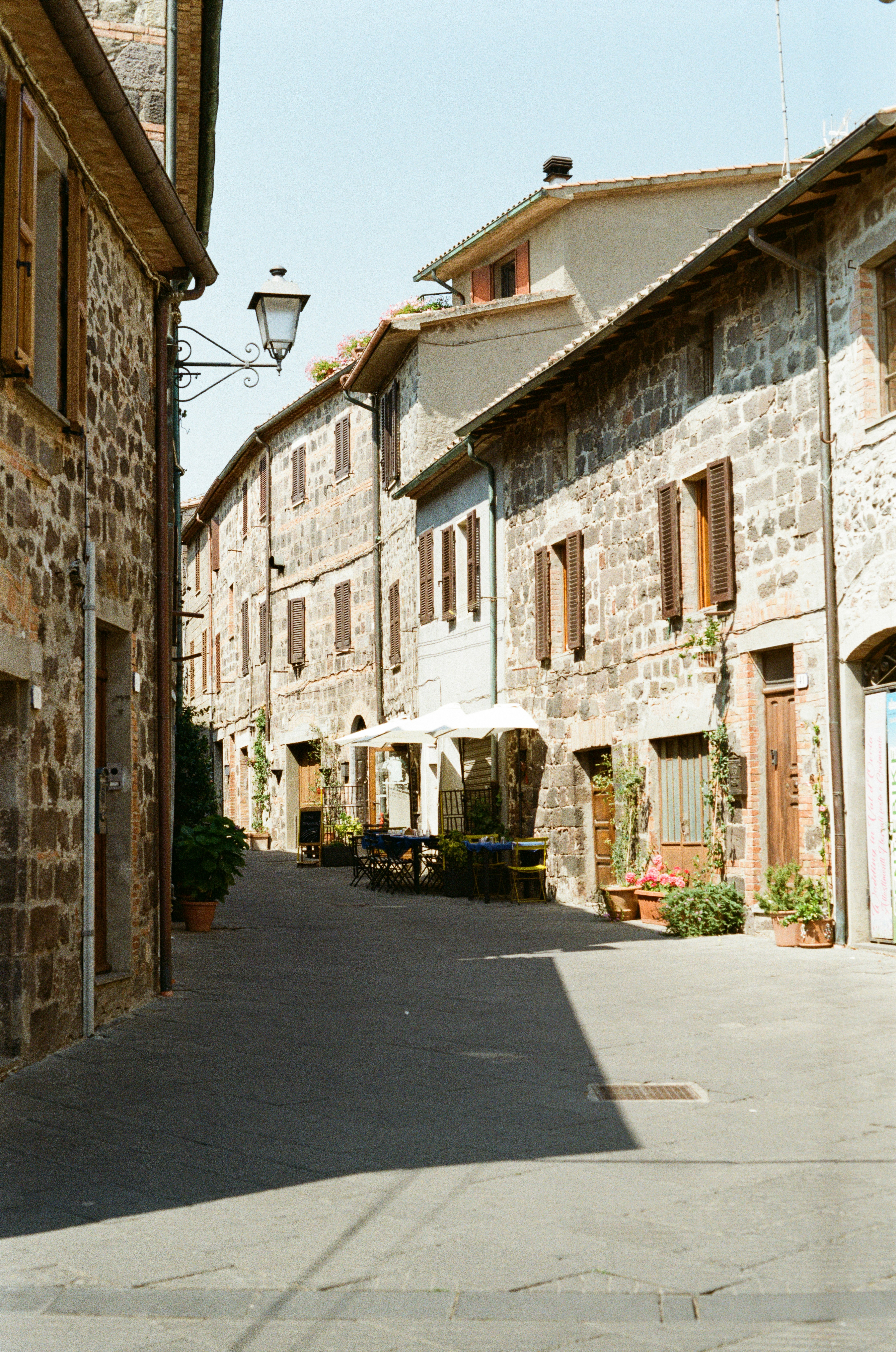Sunlit Cafe Tables Sit Along A Quiet Stone Street In An Old Italian Hill Town. HD mobile wallpaper