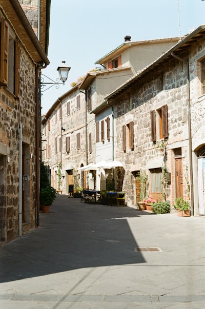 Sunlit Cafe Tables Sit Along A Quiet Stone Street In An Old Italian Hill Town. wallpaper preview