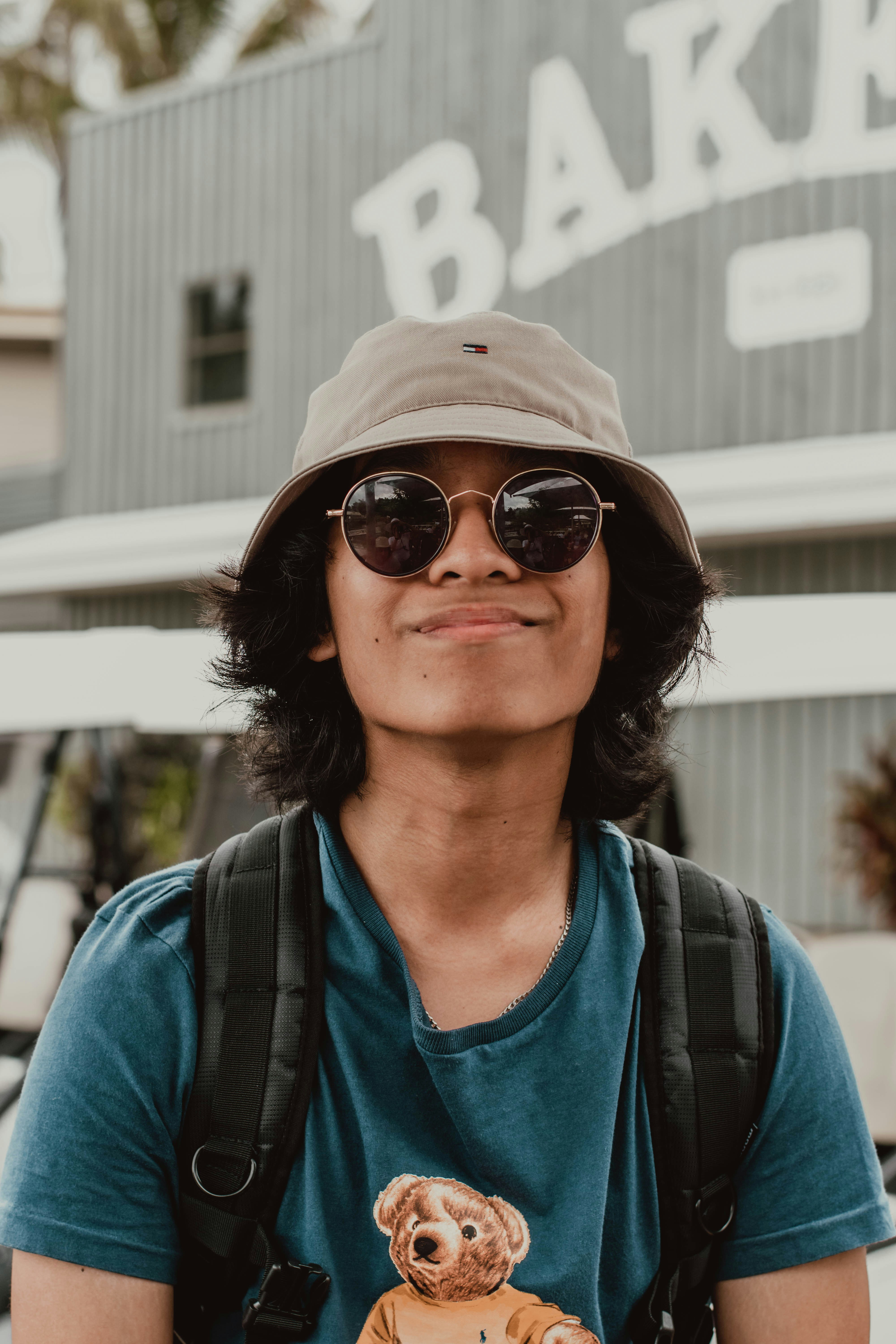 Young Man In Hat And Sunglasses Smiling Near A Bakery. HD mobile wallpaper