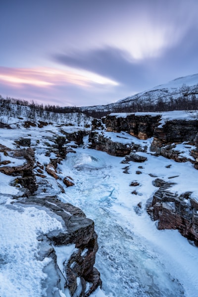 Icy River Winding Through A Snow-covered Canyon At Dusk. wallpaper preview