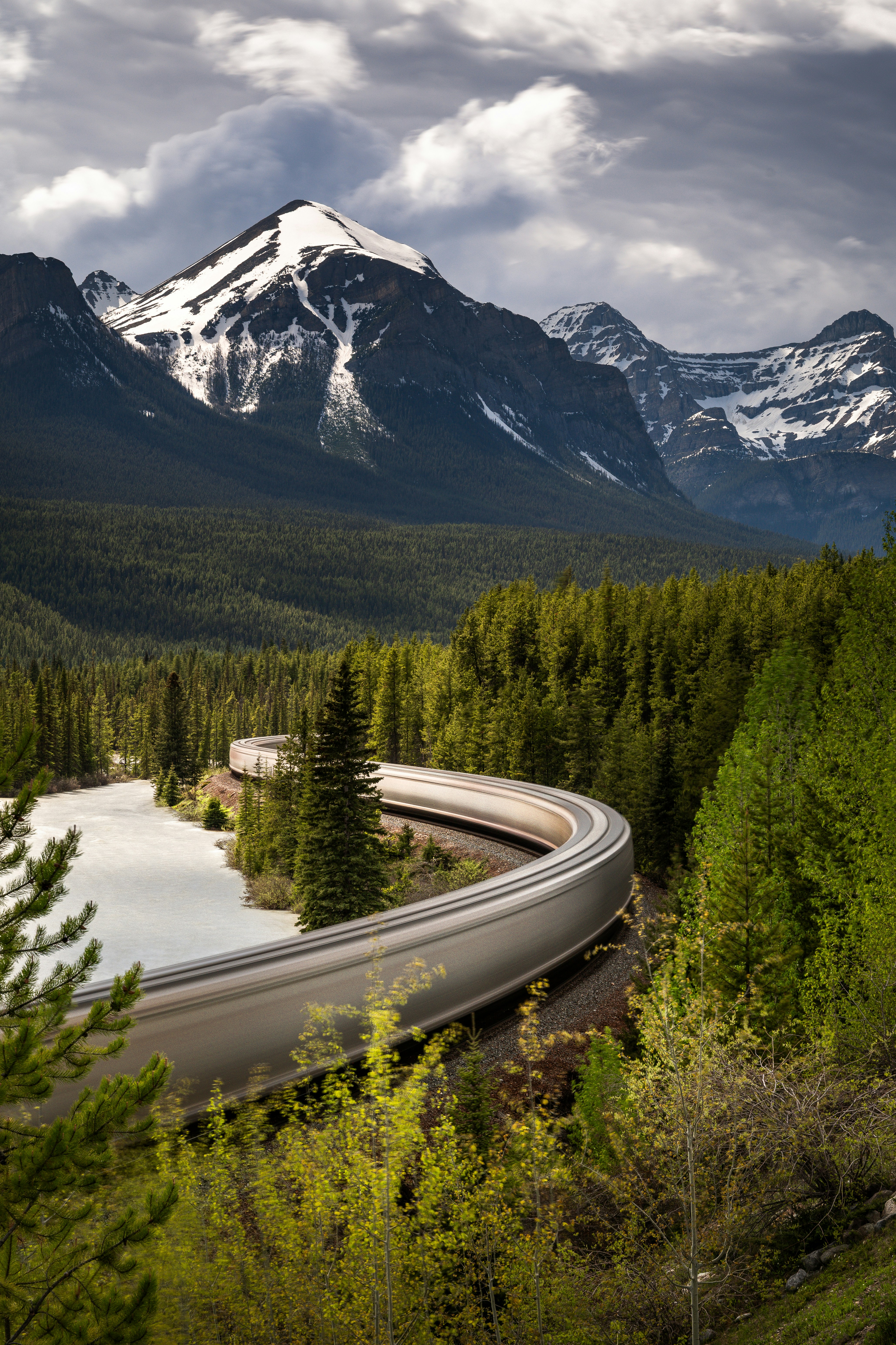 A Train Winds Through A Lush Forest With Snow-capped Mountains. HD mobile wallpaper