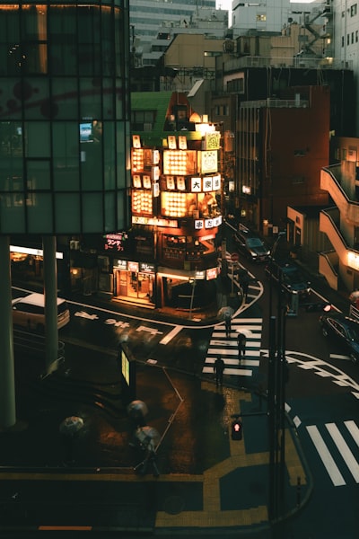 Rainy City Street At Night With Illuminated Buildings.
