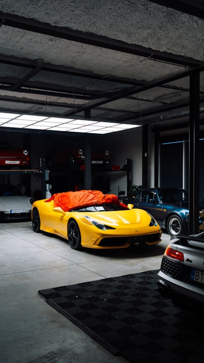 Yellow Sports Car Covered With Orange Tarp In Garage. wallpaper preview