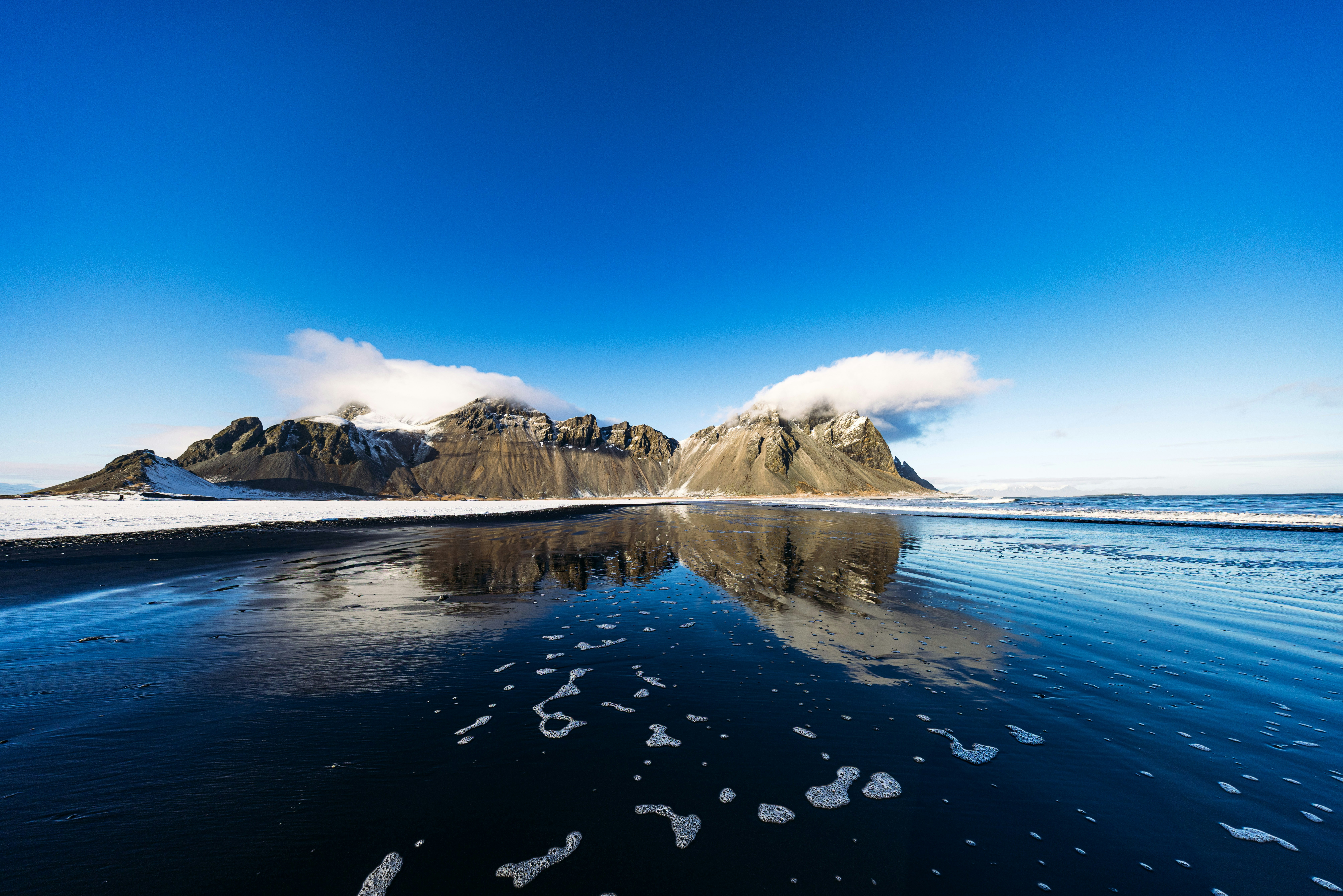 冬日海滩上的水面映照雪满山峦手机壁纸高清图片