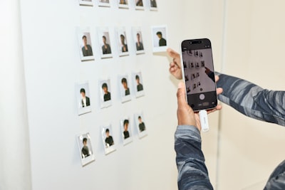 Person Photographs Small Pictures On A White Wall With Phone. wallpaper preview