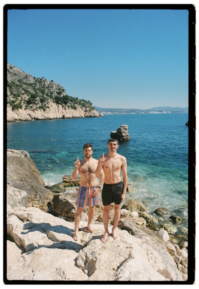 Two Men Standing On Rocks By The Ocean wallpaper preview