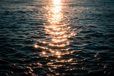 Sunlight Path Reflecting On Dark, Rippling Ocean Water At Sunset.