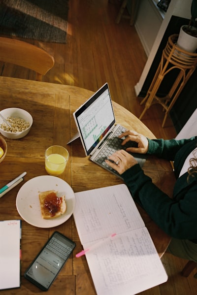 Person Working On Laptop At Wooden Table With Breakfast. wallpaper preview
