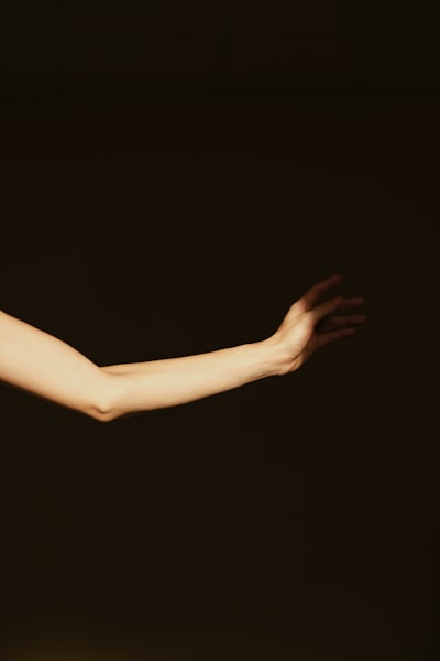 A Person's Arm And Hand Extended In A Dark Setting. wallpaper preview