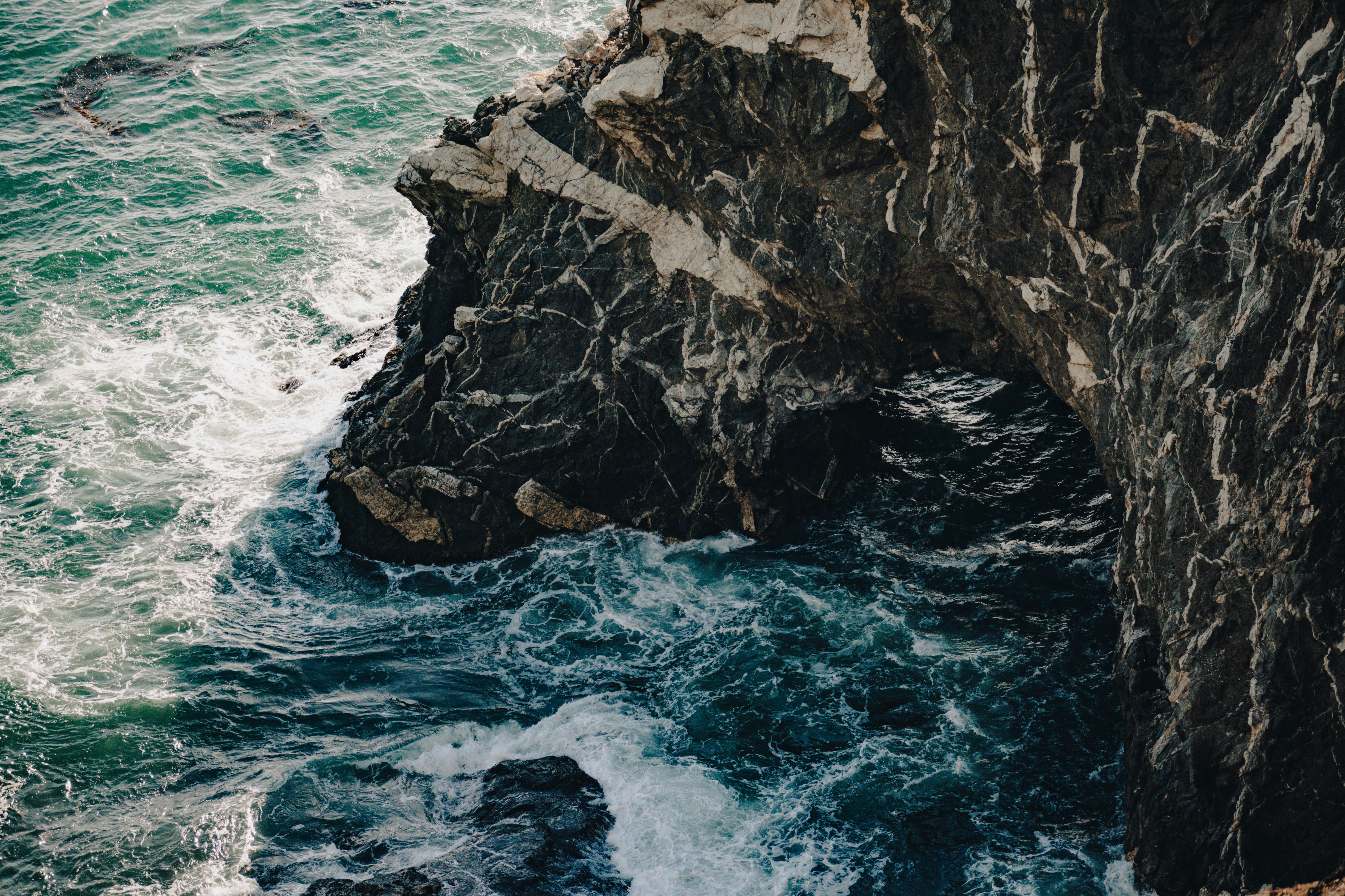 Dark, Rugged Cliffs Meet Foamy, Turbulent Ocean Water. HD mobile wallpaper