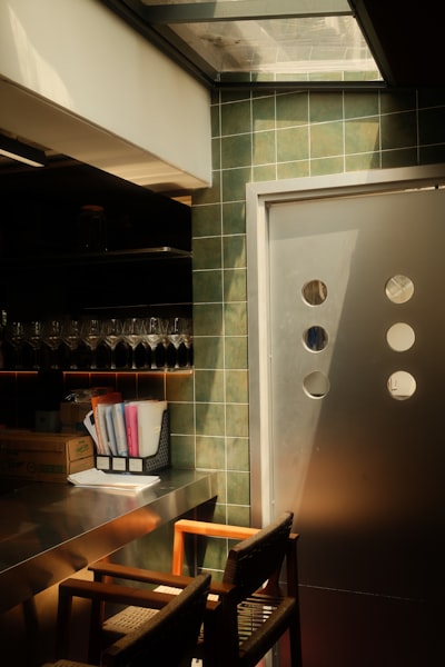 Sunlit Modern Bar With Green Tiled Wall And Metal Door. wallpaper preview